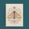 Agenda ilustrada con polilla simétrica en tonos tierra, rodeada de elementos botánicos sobre fondo crema.